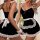 Woman modeling black maid lingerie set with white lace trim, bow belt, and wrist cuffs for playful bedroom roleplay.