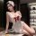 Woman wearing white cherry romance lingerie dress with red bow, lace trim, and maid headpiece in elegant room setting.