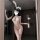 Woman wearing white lace bunny bodysuit with mesh panels and rhinestones, holding feather accessory in modern room setting.