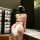 Woman wearing a leopard print lingerie set with halter neck and tie-belt details, showcasing the back view in a modern room s...