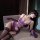 Woman reclining in purple luxury lace satin lingerie set with underwire push-up bra and sheer thigh-high stockings.