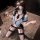Woman in blue and black secretary-style lingerie set with lace mask, front snap closure, sheer stockings, and feather wand.