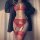 Woman wearing red lace lingerie set with garter belt and stockings, open-crotch design, styled under a black blazer.