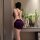 Woman in purple starry night dance lingerie set with lace bodycon skirt, posing by a table with flowers and champagne.