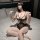Woman in baiyueguang lingerie set with sheer mesh, ruffles, and chain detail on bed.