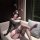 Woman in qingshe alluring lace bodysuit, off-shoulder black lingerie with lace trim and bunny ears, posing on sofa.