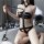 Woman wearing black latex-style corset and holding whip, backless halter bodysuit for couples role play.