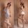 Woman modeling white sensual nurse costume set with deep v cutout, fishnet stockings, and nurse hat in soft romantic setting.
