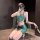 A woman poses in a luxurious green exotic lingerie set, featuring a sheer mesh bra with floral embroidery and matching satin ...