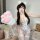 A woman poses with a plush white paw glove, wearing a floral-patterned sleepwear set featuring adjustable straps. the outfit ...