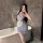 A woman poses in a bathroom wearing a light blue maid costume, holding a glass of champagne. the outfit features delicate lac...