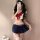 A woman poses in a playful sailor-themed outfit, featuring a white crop top with a red bow and navy pleated skirt, perfect fo...