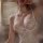 Woman wearing white low-cut push-up lace babydoll with sheer panels and underwire support, styled with layered necklaces.