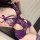 Woman wearing purple lace bodysuit with sheer panels and bow details.