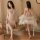 Woman modeling sheer lace babydoll sleep set with garter belt, deep v neckline, and flowing robe in elegant bedroom setting.