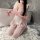 A woman wearing a pink maid costume holding a pink whip, posing on a fluffy rug next to a bathtub. the outfit features lace d...