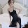 A woman poses elegantly on a bed wearing a black sheer lace mesh sleep dress, featuring adjustable straps and a flowing desig...