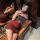 A woman poses elegantly in a red new year lingerie sleep dress, featuring sheer lace bodysuit design with padded straps and b...