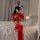A woman poses on a bed wearing a glossy red pvc high-stretch zip-front bodysuit, perfect for pole dancing and nightclub wear.