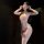 Woman wearing pink luxury lace sensual bodysuit with sheer panels, lace trim, and matching eye mask in dim lighting.