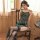 A woman sits on a wooden chair wearing a qianyu mo silk-look lace bodysuit adorned with chinese-inspired peacock embroidery. ...