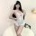 Woman wearing white lace open-crotch bodysuit with sheer cutouts and flirty ruffles, styled for sensual allure sleepwear.
