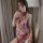 Woman wearing sheer red butterfly lace sleepwear set with matching bralette, posing in elegant lounge setting.