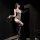 Woman in chao mu qing qu sheer mesh bodysuit with lace, holding a whip, posing seductively in dim lighting.