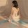 A woman sits facing away from the camera, wearing a sheer chiffon chinese traditional doudou lingerie set. the delicate fabri...