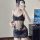 A woman poses in a black lace bodysuit with an open design, featuring delicate floral patterns and thin straps. the outfit hi...