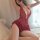 Woman wearing red lace sleep dress with open-crotch design, posing seductively on bed — romantic lingerie for women.