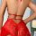 Woman wearing red lace sleep dress with open-crotch design, showcasing backless style and delicate floral embroidery.
