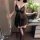 Woman wearing black sheer lace sleep dress with open-crotch and rear exposure design, holding wine glass beside floral arrang...