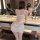 A woman stands by a bathroom mirror wearing a luxurious white sheer lace lingerie set, featuring a romantic design with ties ...