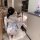 A woman in a japanese-style couples pajama set with floral patterns and a large bow, reaching into a refrigerator. the outfit...