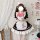 A woman wears a japanese-style maid dress featuring black and white lace with a pink bow apron, perfect for lolita cosplay.