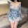 Woman wearing light blue floral kimono-style sleepwear set with bow waist tie, sheer fabric, and off-shoulder design.