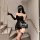 Woman in black lace halter bodycon mini dress with satin finish, long gloves, and thigh-high stockings on staircase.