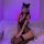Woman in purple lighting wearing black lace maid costume set with matching lingerie, thigh-highs, and cat ears accessory.