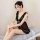A woman sits elegantly on a bed wearing a sheer black lace nightgown with delicate ruffles and side slits, perfect for cozy e...