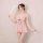 A woman poses elegantly in a sheer pink lace sleepwear set, featuring delicate ruffles and a charming bow detail, perfect for...