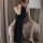 A woman poses elegantly in a black high-slit cheongsam-style nightwear, featuring sheer details and a flowing design, perfect...