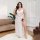 A woman poses elegantly in a plus-size sexy lace long dress set, featuring a semi-sheer backless design and transparent eleme...