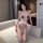 Woman wearing muran sensual lace bodysuit, open-crotch tight sleepwear with red trim and bold chest text, posing on sofa.