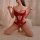 A woman poses in a red lace bodice and matching panties, showcasing a vintage maid uniform outfit ideal for cosplay or role p...