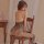 Woman wearing black lace night passion lingerie set, sitting on wooden chair in bedroom setting.