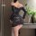 Woman wearing black night silk lace bodycon mini dress with sheer long sleeves and one-shoulder design, posing indoors near g...