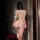 Woman wearing night-silk sensual lace open-crotch sleepwear set – sheer bodysuit and matching thong, back view in dim room.