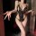 Woman wearing black lace bodysuit with open crotch, holding wine glass, in dimly lit room.