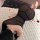 Woman wearing black sheer bodycon dress with rose petals on white rug, showcasing night silk sensual lingerie set.